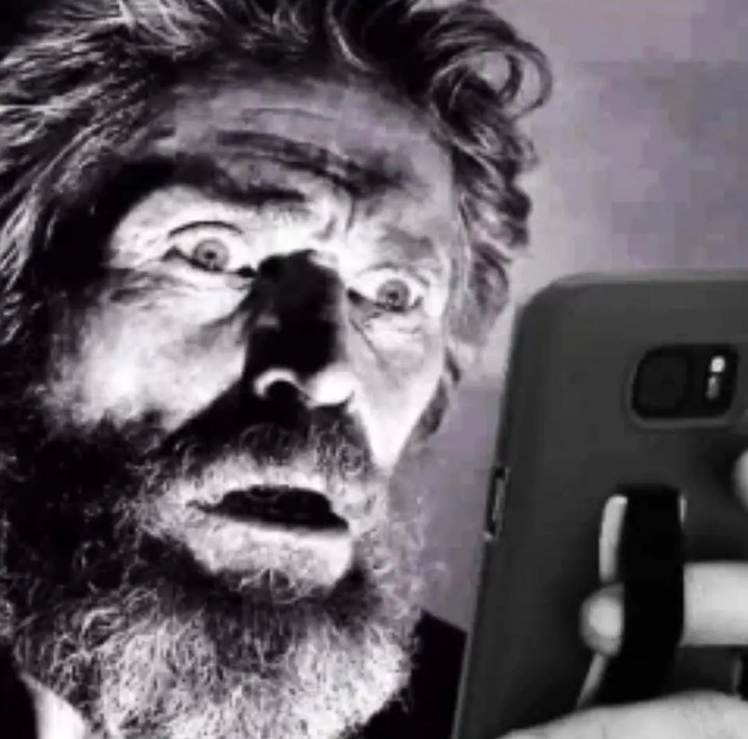 man looking at his phone with a shocked face, with the lighting focusing on his eyes