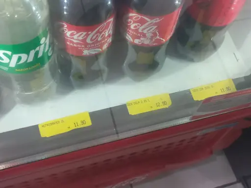 Uma geladeira de mercado com refrigerantes, tem três etiquetas em que está escrito: Refrigantes, Coca Cola 2 25L e Coco Coa Zero